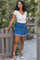 woman wearing a white short sleeve top and a blue denim skirt with front buttons and frayed hem
