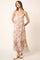 woman wearing a floral print maxi dress with thin straps and a flowing hem, styled with flat sandals