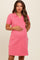 woman wearing a pink short sleeve maternity dress with a collar and holding her baby bump