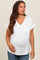 woman wearing a white maternity top with a pocket, smiling and showing her baby bump