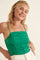 woman wearing a bright green ruched tank top with spaghetti straps and a smiling expression