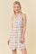 woman wearing a beige and brown plaid sleeveless dress with a collared neckline and button front detail