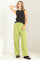 woman wearing a black sleeveless top and high-waisted light green wide-leg trousers