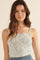 woman wearing a light blue smocked crop top with thin straps and a ruffled neckline