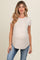 woman wearing a light beige short sleeve maternity top and showing her baby bump