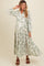 woman wearing a long sleeve floral maternity dress with a tiered skirt and tassel details, highlighting her baby bump