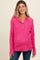 woman wearing a bright pink ribbed maternity sweater with button details and a visible baby bump