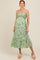 woman wearing a green and white leaf print maternity dress with a halter neckline and tiered skirt, showing her baby bump