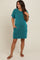 woman wearing a teal striped maternity dress with short sleeves and pockets, standing in a relaxed pose