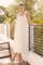 woman wearing a white midi dress with ruffled straps and floral details, standing by a railing outdoors