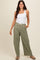 woman wearing a white tank top and green checkered wide-leg pants with a drawstring waist