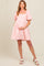 woman wearing a pink floral embroidered maternity dress and holding her baby bump