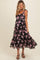 woman wearing a floral black maternity dress with adjustable straps and a tiered hem, showcasing her baby bump