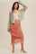 woman wearing a gray knitted cardigan over a cream tank top and a blush pink tiered skirt with lace details