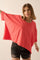 woman wearing a coral oversized t-shirt with short sleeves and black denim shorts