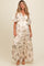 woman wearing a cream floral maternity maxi dress with flutter sleeves and a tiered skirt, showcasing her baby bump