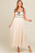 woman wearing a cream-colored maternity maxi dress with black piping and tie straps