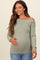 woman wearing an olive green off-the-shoulder maternity top and holding her baby bump