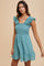 woman wearing a light teal smocked dress with ruffle straps and a tiered skirt