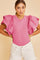 woman wearing a pink short sleeve bodysuit with ruffle sleeves and white distressed shorts