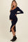 woman wearing a navy blue ribbed maternity dress with a side slit, showcasing her baby bump