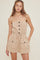 woman wearing a tan sleeveless romper with buttons and front pockets, styled with a drawstring waist