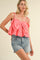 woman wearing a pink crop top with a large bow detail and buttons, paired with light blue denim shorts