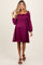 woman wearing a purple short sleeve maternity dress with a smocked bodice and puff sleeves, showcasing her baby bump