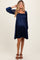 woman wearing a navy blue maternity dress with long sleeves and a gathered bust, showcasing her baby bump