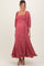 woman wearing a pink smocked maternity dress with puff sleeves and ruffled hem, highlighting her baby bump