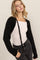 woman wearing a black cable knit cardigan over a white long sleeve top and black high-waisted jeans