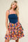 woman wearing a denim bodice dress with a colorful ruffled floral skirt