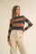 woman wearing a brown and navy striped cropped sweater with long sleeves and high-waisted cream trousers