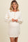 woman wearing a cream oversized maternity sweater dress with button details and a visible baby bump