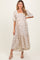 woman wearing a light beige floral maternity dress with puff sleeves and tiered skirt, showcasing her baby bump