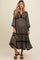 woman wearing a black floral maternity dress with puff sleeves and tiered skirt, highlighting her baby bump