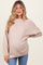 woman wearing a light beige oversized maternity sweater with long sleeves and a visible baby bump