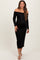 woman wearing a black off-the-shoulder maternity dress with long sleeves and a fitted silhouette, showing her baby bump