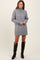 woman wearing a gray turtleneck sweater dress and black knee-high patent leather boots