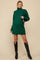 woman wearing a dark green maternity sweater dress with a turtleneck and oversized fit, holding a small handbag