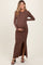 woman wearing a chocolate brown ribbed long sleeve maternity dress with a side slit and holding her baby bump