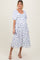 woman wearing a white maternity dress with blue floral print and puff sleeves, showing her baby bump