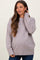 woman wearing a light lavender oversized maternity sweater with ribbed hem and cuffs, holding her hair back