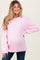 woman wearing a light pink oversized maternity sweater with a visible baby bump