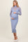 woman wearing a light blue maternity dress with a fitted silhouette and long sleeves, showing her baby bump