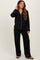 woman wearing a black maternity pajama set with white piping, featuring long sleeves and relaxed fit pants, baby bump visible