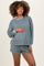 woman wearing a blue and gray checkered maternity loungewear set with long sleeves and shorts, holding her baby bump