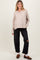 woman wearing a beige maternity long sleeve henley top with buttons and distressed black maternity jeans
