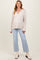 woman wearing a beige ribbed maternity sweater and light blue flared jeans, showcasing a visible baby bump