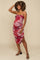 woman wearing a red and pink patterned maternity dress with a fitted silhouette and spaghetti straps, showing her baby bump